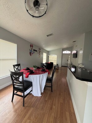 A dining area with a table set for four, a ceiling fan, and a kitchen area with a sink and countertop. - Cozy Home minutes from Disney (Davenport)