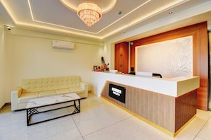 A reception area with a reception desk, a sofa, and a chandelier.