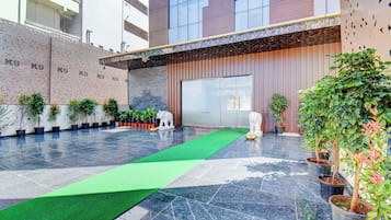 Un vestíbulo de hotel con alfombra verde, plantas en macetas y una estatua.