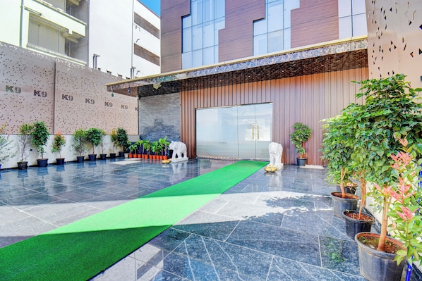 A hotel lobby with a green carpet, potted plants, and a statue.