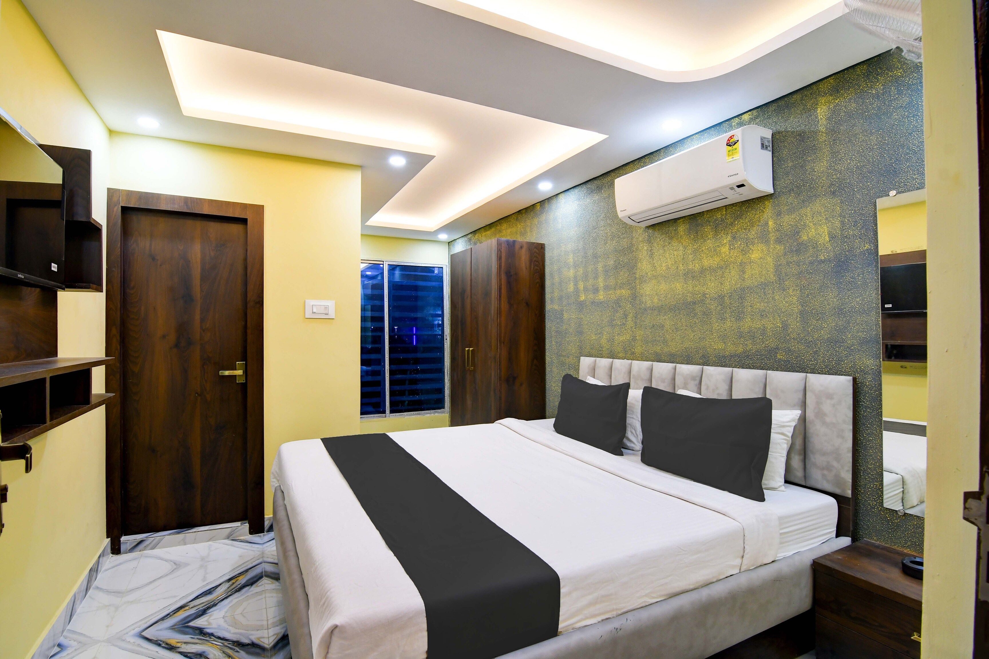 Habitación de hotel con cama, armario, televisión y aire acondicionado.