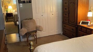 Un dormitorio con cama, una silla, armario, cómoda y mesita de noche.