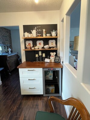 Cocina compacta con encimera de madera, muebles blancos y un mini refrigerador integrado.