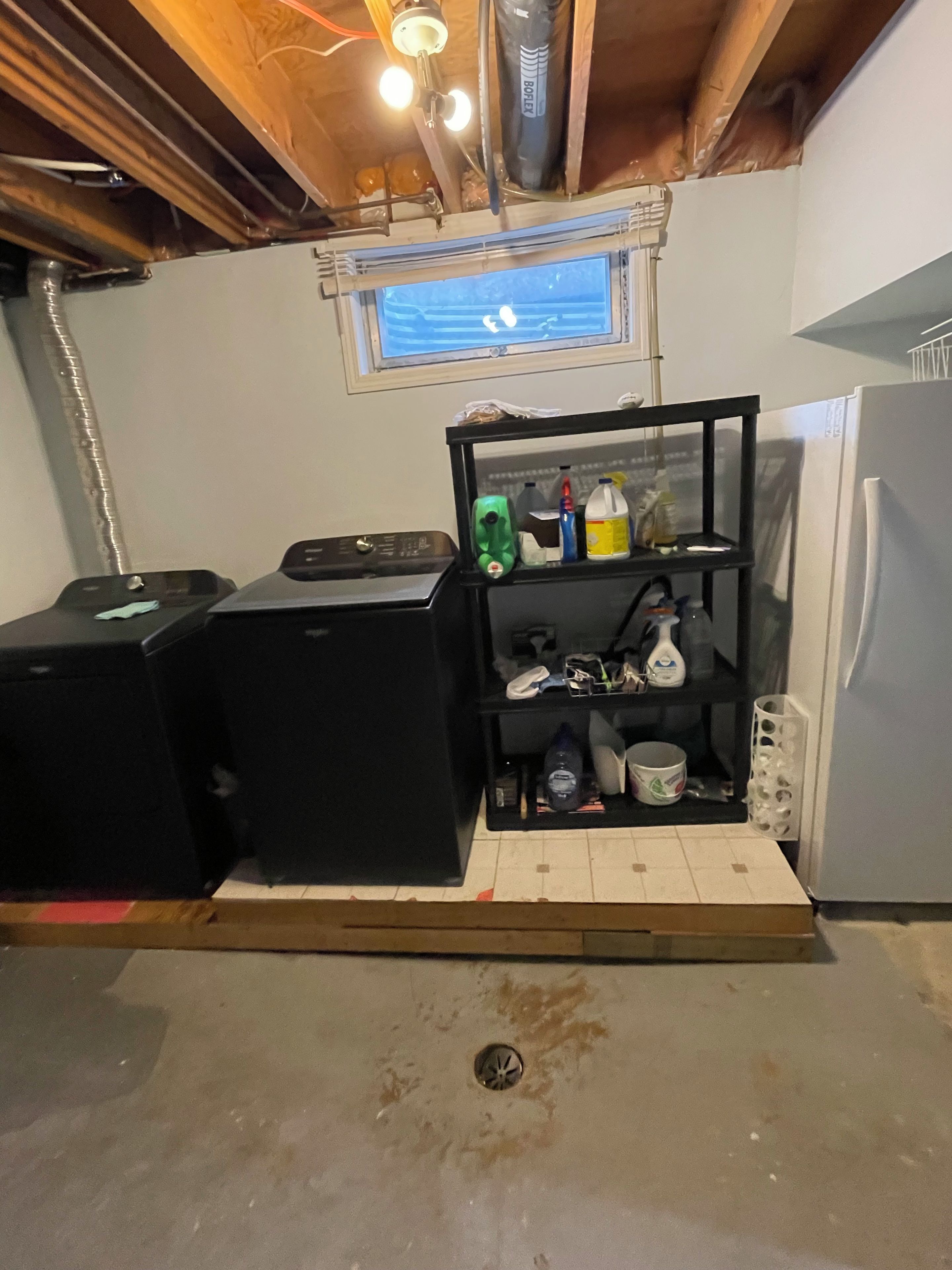 Una cocina compacta con un mueble de estanterías integrado, una ventana encima y un refrigerador.