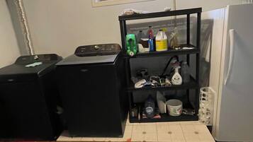 Una cocina compacta con un mueble de estanterías integrado, una ventana encima y un refrigerador.