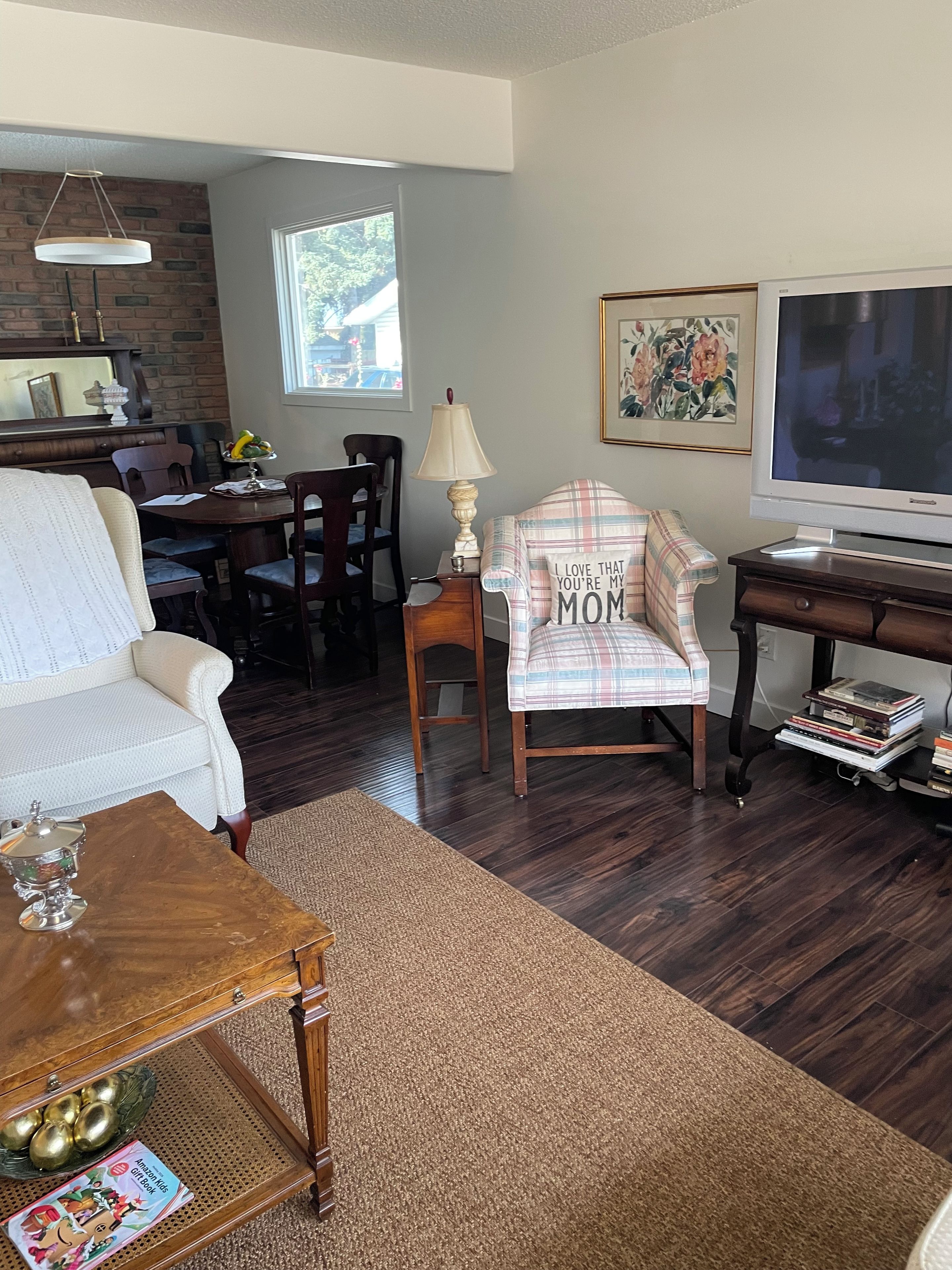 A living room with a sofa, a coffee table, a TV, a lamp, and a chair with a cushion.