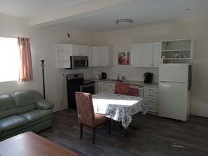 Ein kompakter Wohnbereich mit Küchenzeile, einer Essecke mit Tisch und Stühlen, einer Couch und einer Stehlampe.