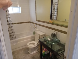 Ein Badezimmer mit einer Badewanne, Toilette, Glaswaschbecken und einer Duschvorhang.