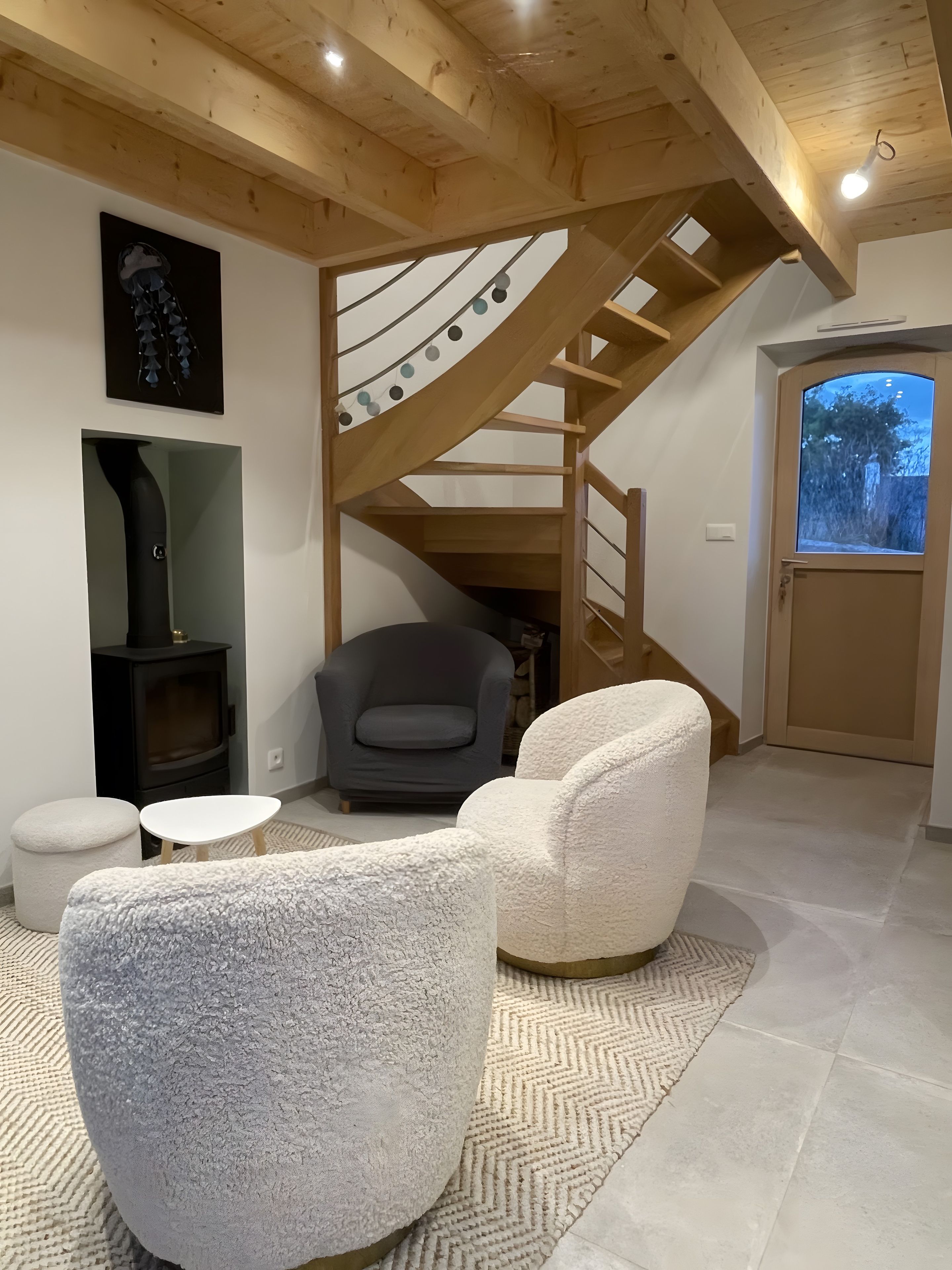 A modern interior with a wooden staircase, a fireplace, and seating area.