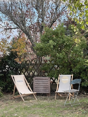 Two outdoor lounge chairs with 'RICARD' branding, positioned under a tree with green and autumn-colored leaves.