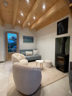 A cozy living room with a fireplace, a sofa, and a large window.
