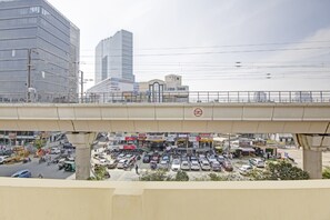 A busy urban street scene with a pedestrian overpass, commercial buildings, and a parking lot.