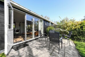 A house with a sliding glass door leading to an outdoor patio area with a table and chairs. - New Listing (Grou)