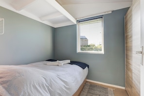 A bedroom with a bed, a window with blinds, a door, and a small rug. - New Listing (Grou)