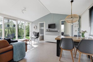 A modern living space with a dining area, kitchen, and a large window overlooking greenery. - New Listing (Grou)