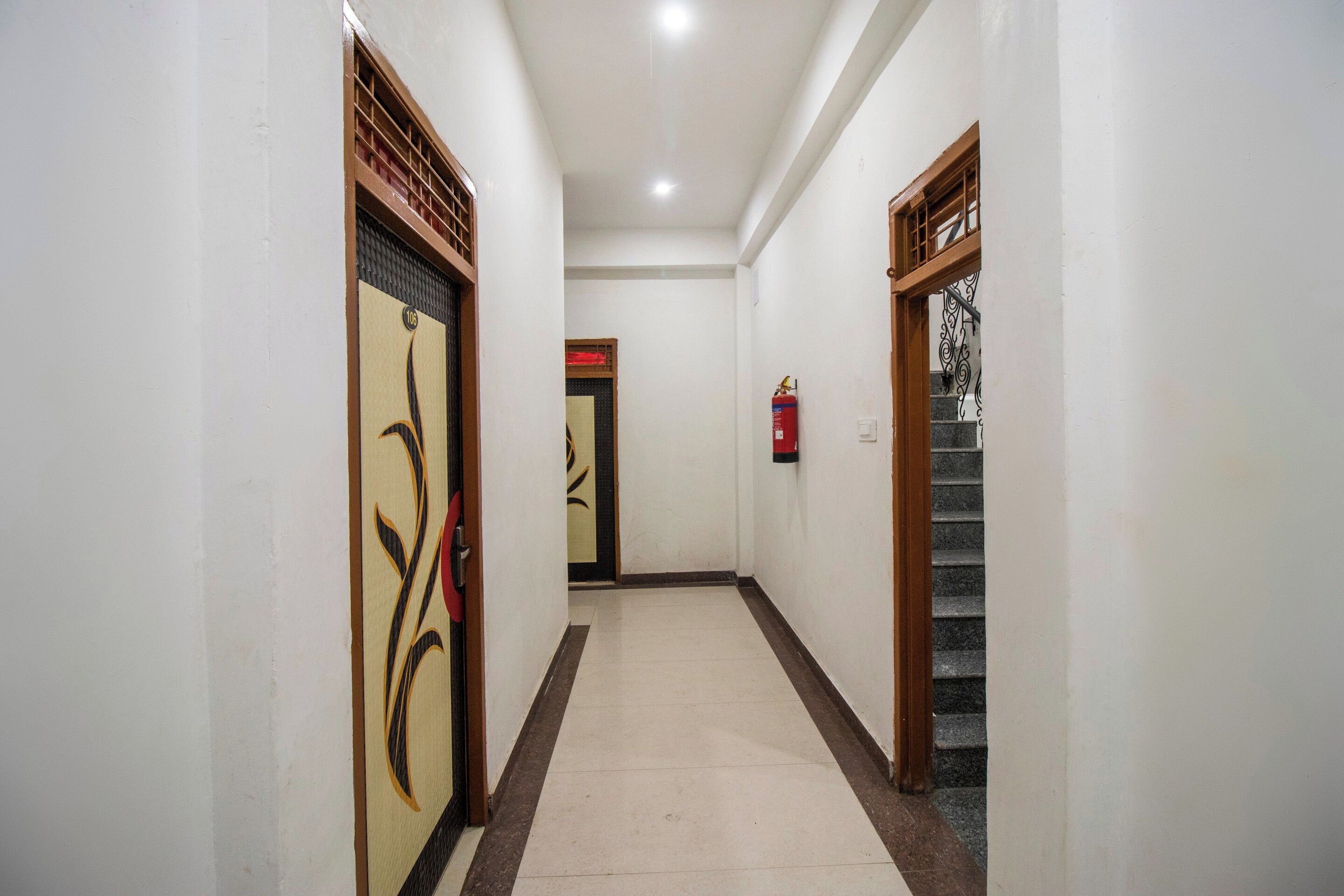 A corridor with doors, a fire extinguisher, and a staircase.