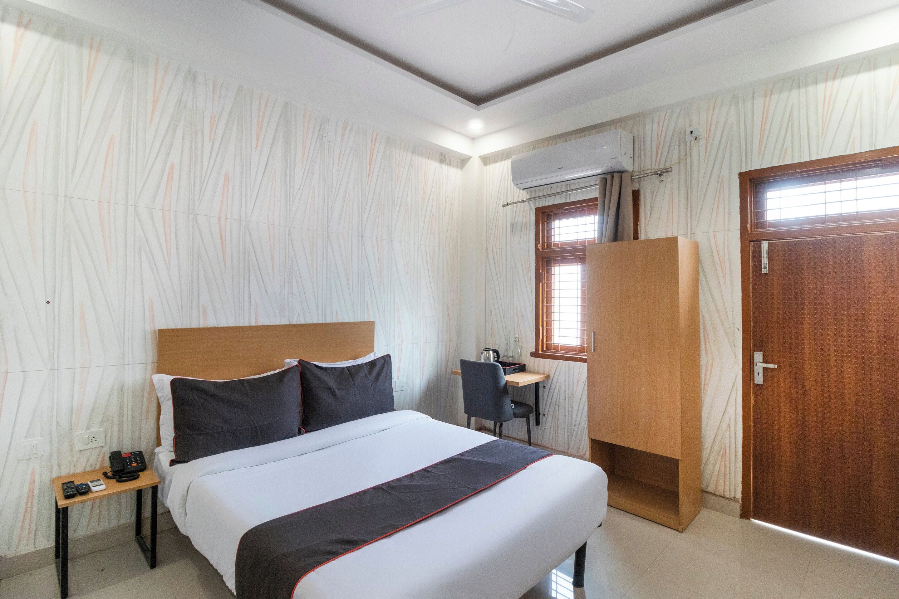 Une chambre d’hôtel équipée d’un lit, d’une table de chevet, d’un bureau, d’une chaise, d’une armoire et d’un appareil de climatisation.