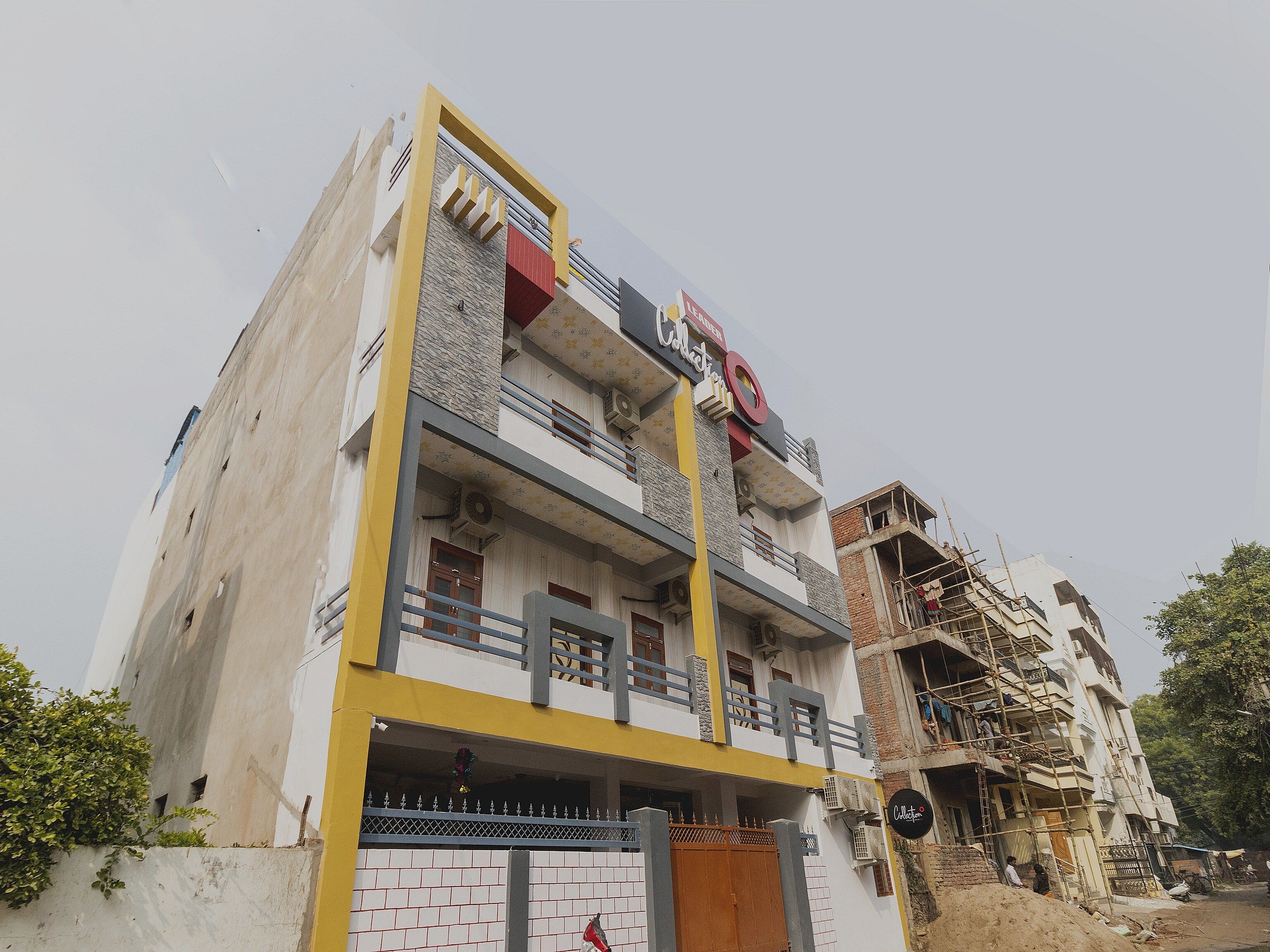 Un edificio de varios pisos con fachada amarilla y blanca, balcones y una puerta visible.