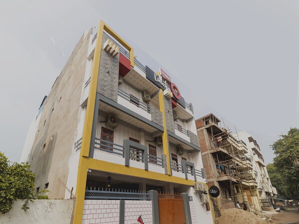 Un edificio de varios pisos con fachada amarilla y blanca, balcones y una puerta visible.