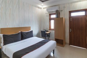 Una habitación de hotel con cama, escritorio, silla y armario.