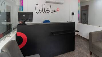 A reception desk with a black counter, a computer monitor, and a wall-mounted phone.