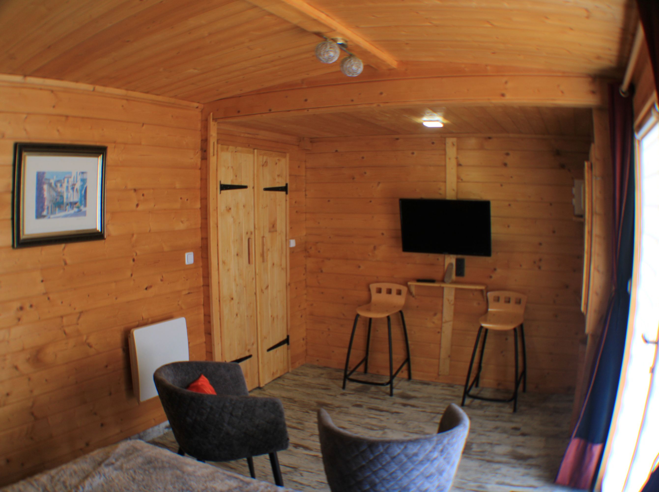 A wooden interior with a TV, two chairs, and a framed picture on the wall.