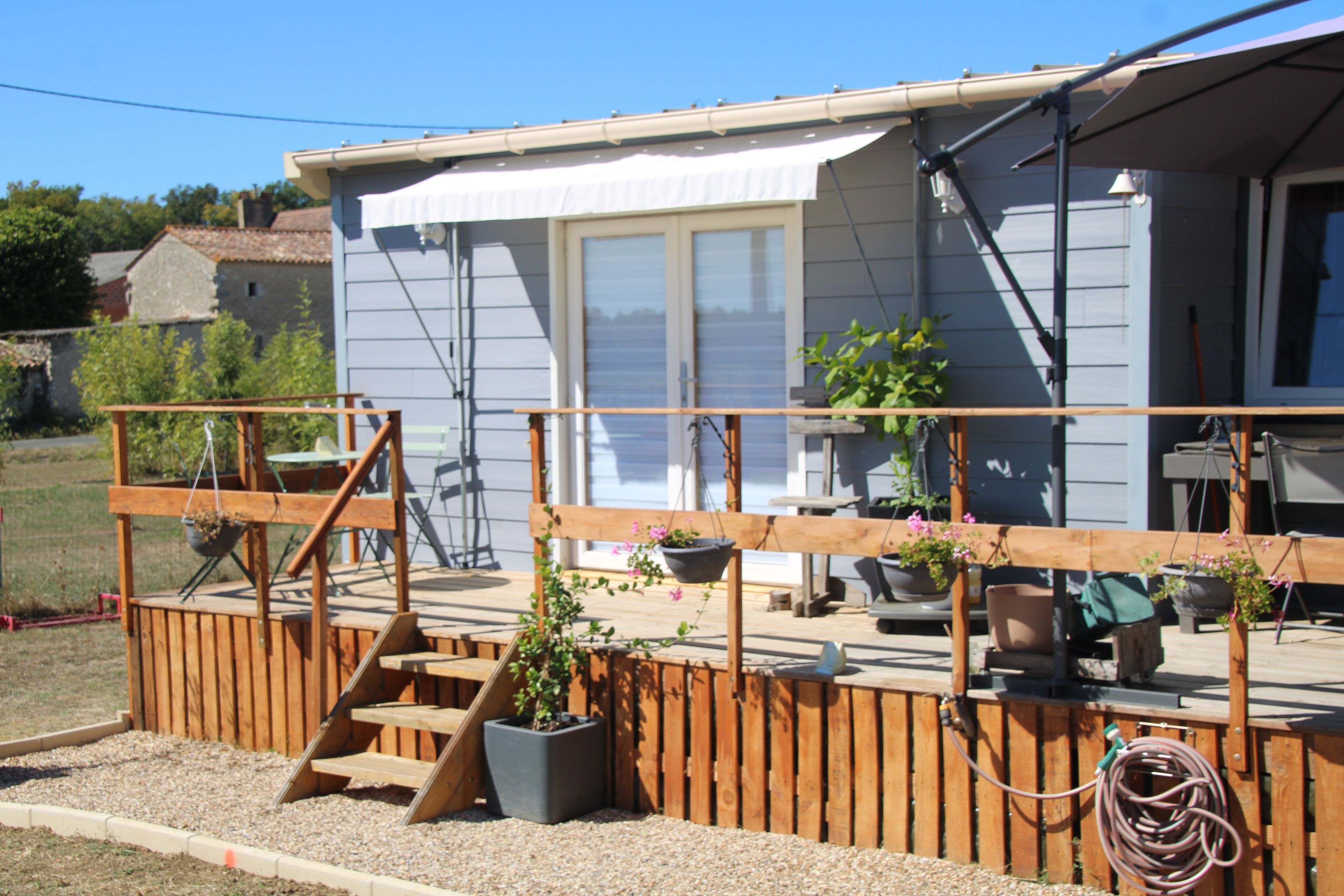 A wooden deck with a railing, potted plants, and a small table.