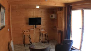 Un intérieur en bois avec un téléviseur, deux tabourets de bar et un canapé.