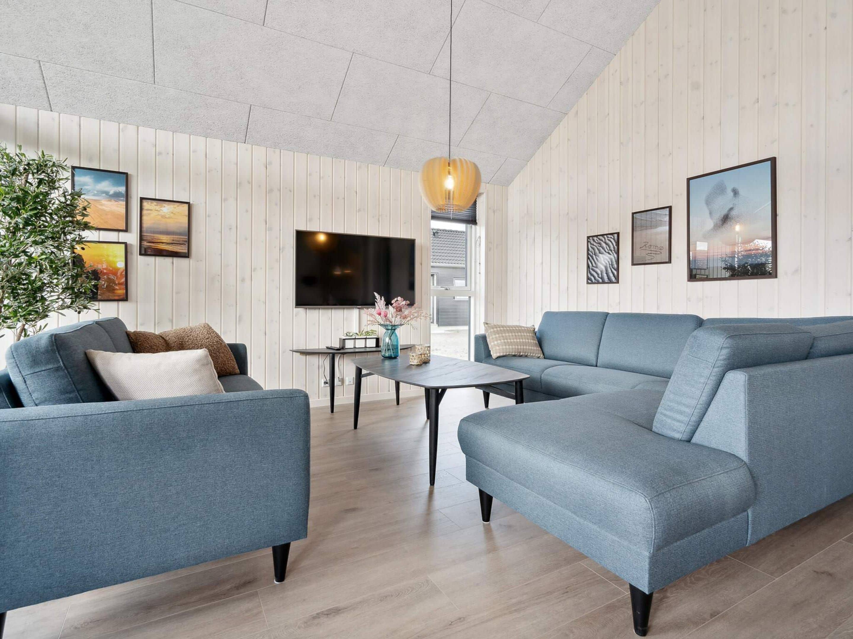 A modern living room with a grey sofa, a coffee table, and a TV mounted on the wall.