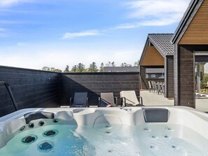 Ein Whirlpool mit Holzterrasse und Sitzgelegenheiten im Freien.
