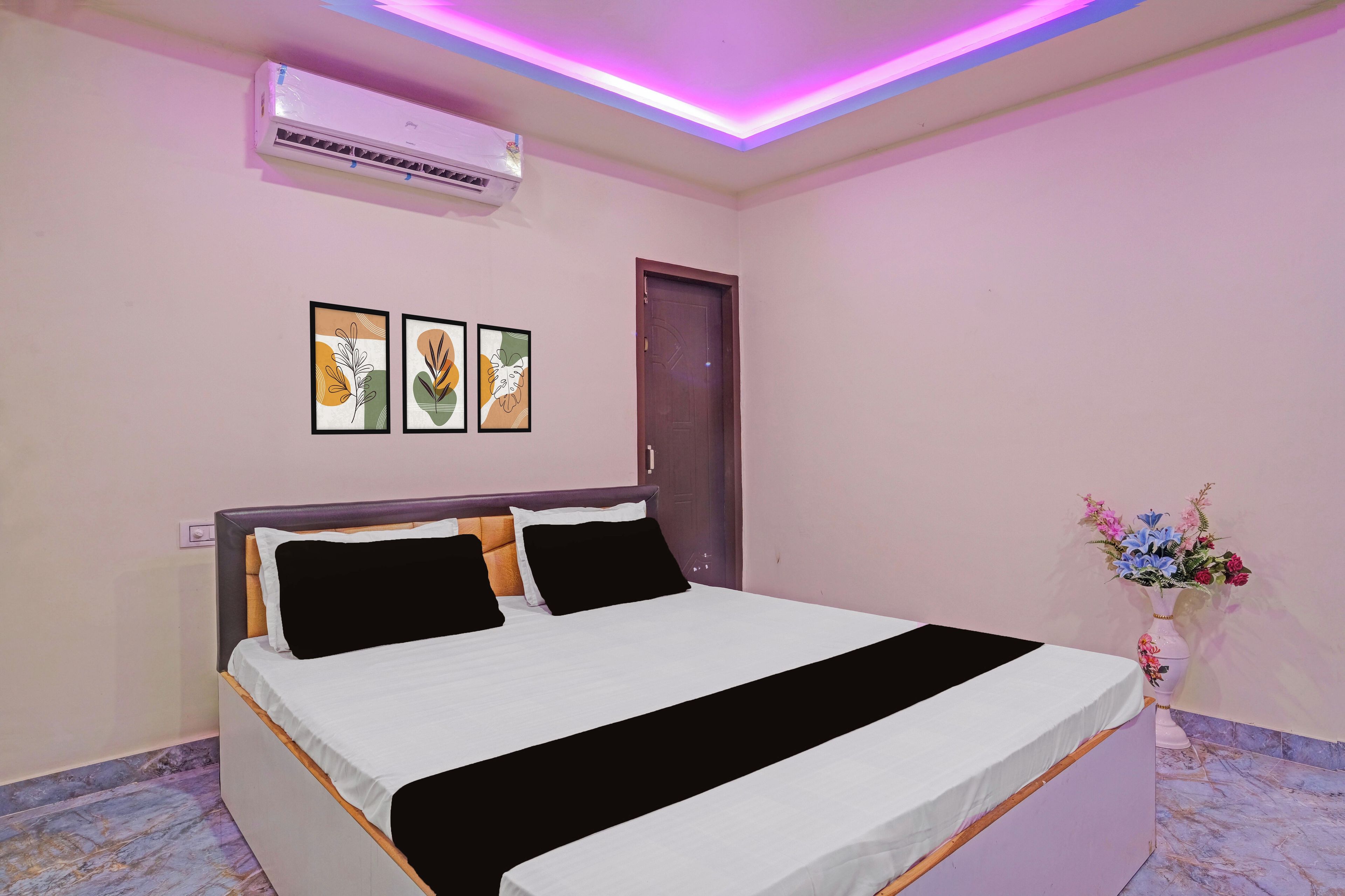 A bedroom with a bed, an air conditioner, and wall art.
