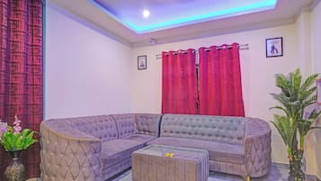Una sala de estar con un sofá modular, una mesa de centro, una cortina roja y una cámara de seguridad instalada en la pared.