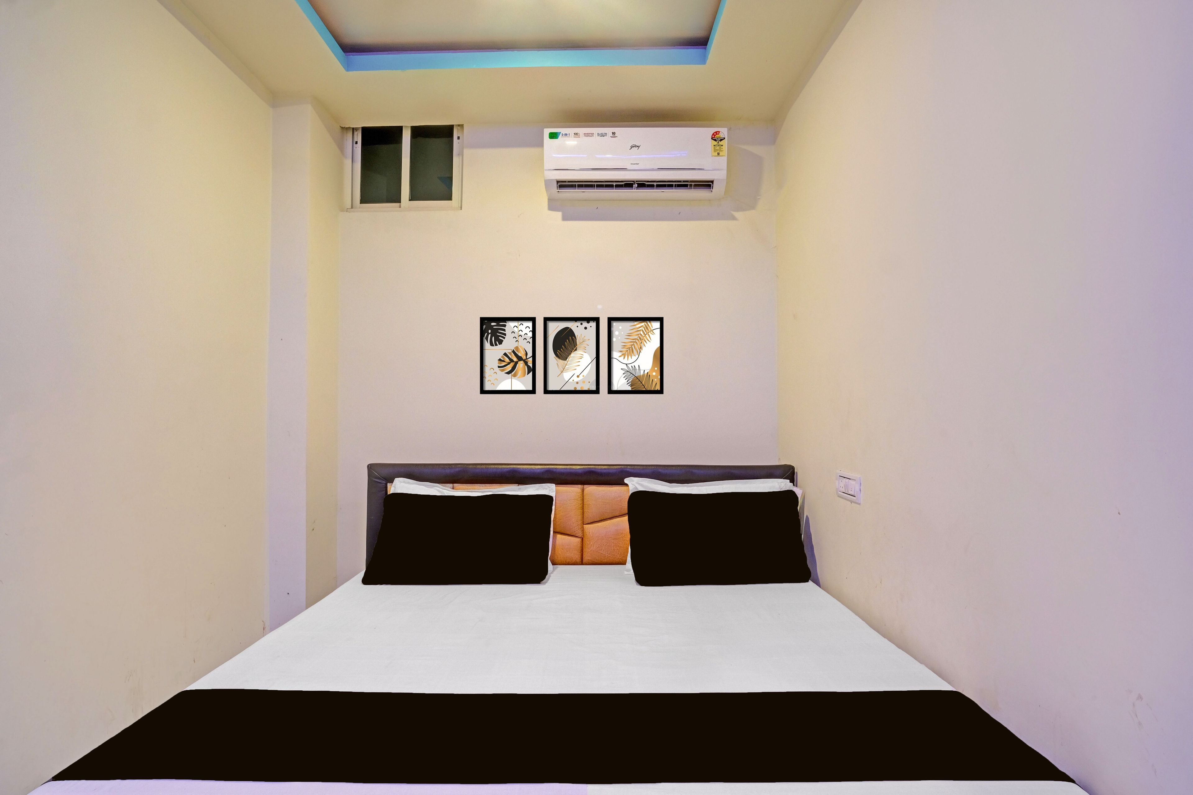 Un dormitorio con cama, unidad de aire acondicionado y tres cuadros en la pared.