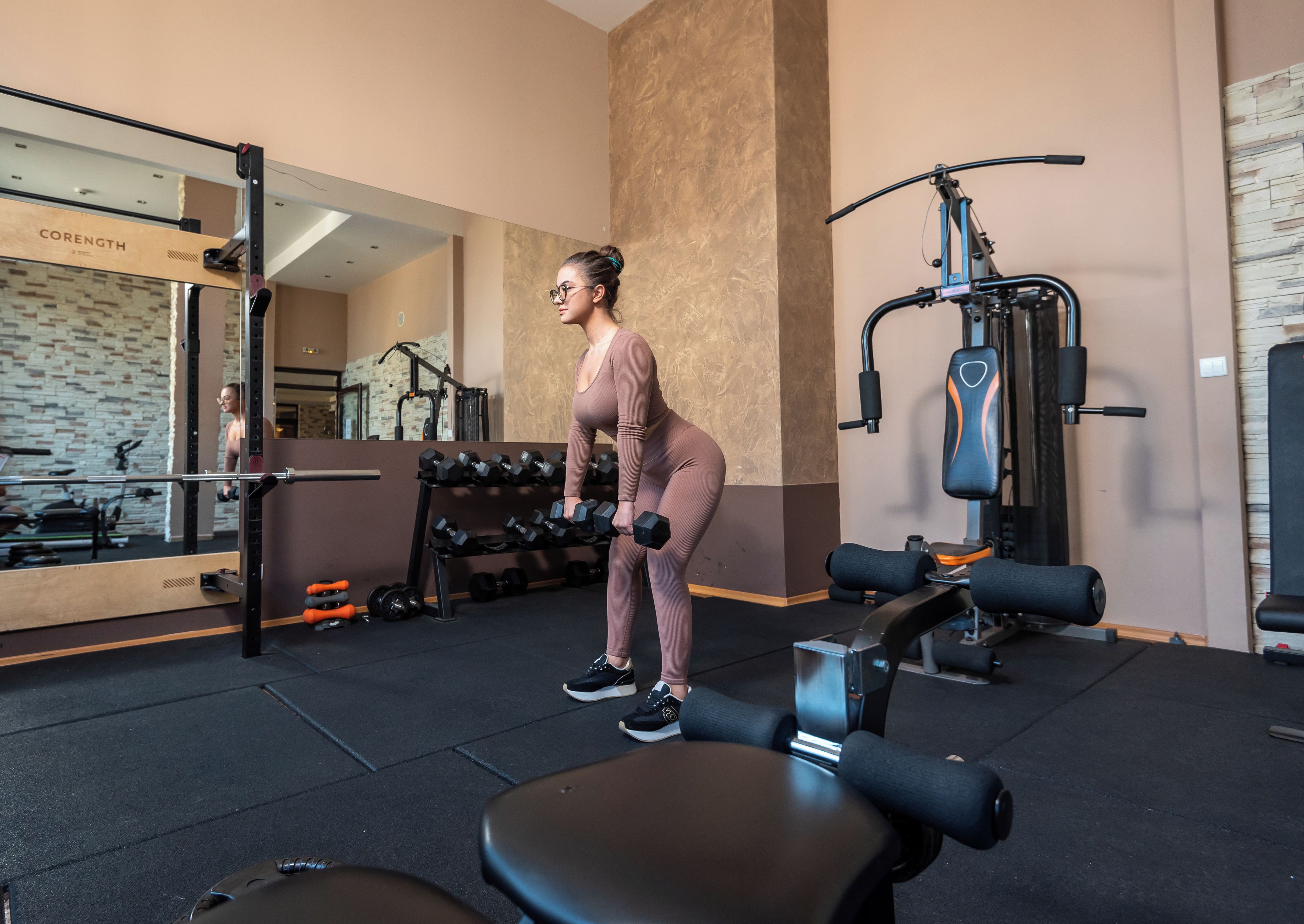 A gym with exercise equipment, a mirror, and a wall with a 'CORENGTH' sign.