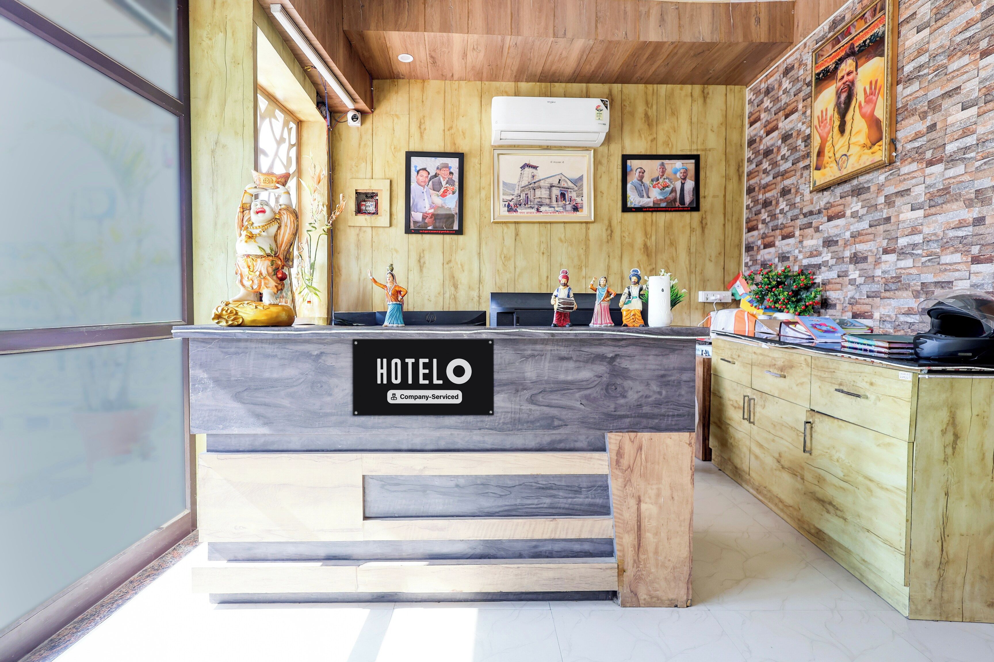 Ein Hotelrezeptionstresen mit Holzvertäfelung, eine Schilderung, dass es sich um ein betriebliches Hotel handelt, und eine Backsteinwand mit gerahmten Bildern.
