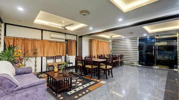 Amplia sala de estar con sofá, mesa de comedor, sillas y una estatua decorativa.