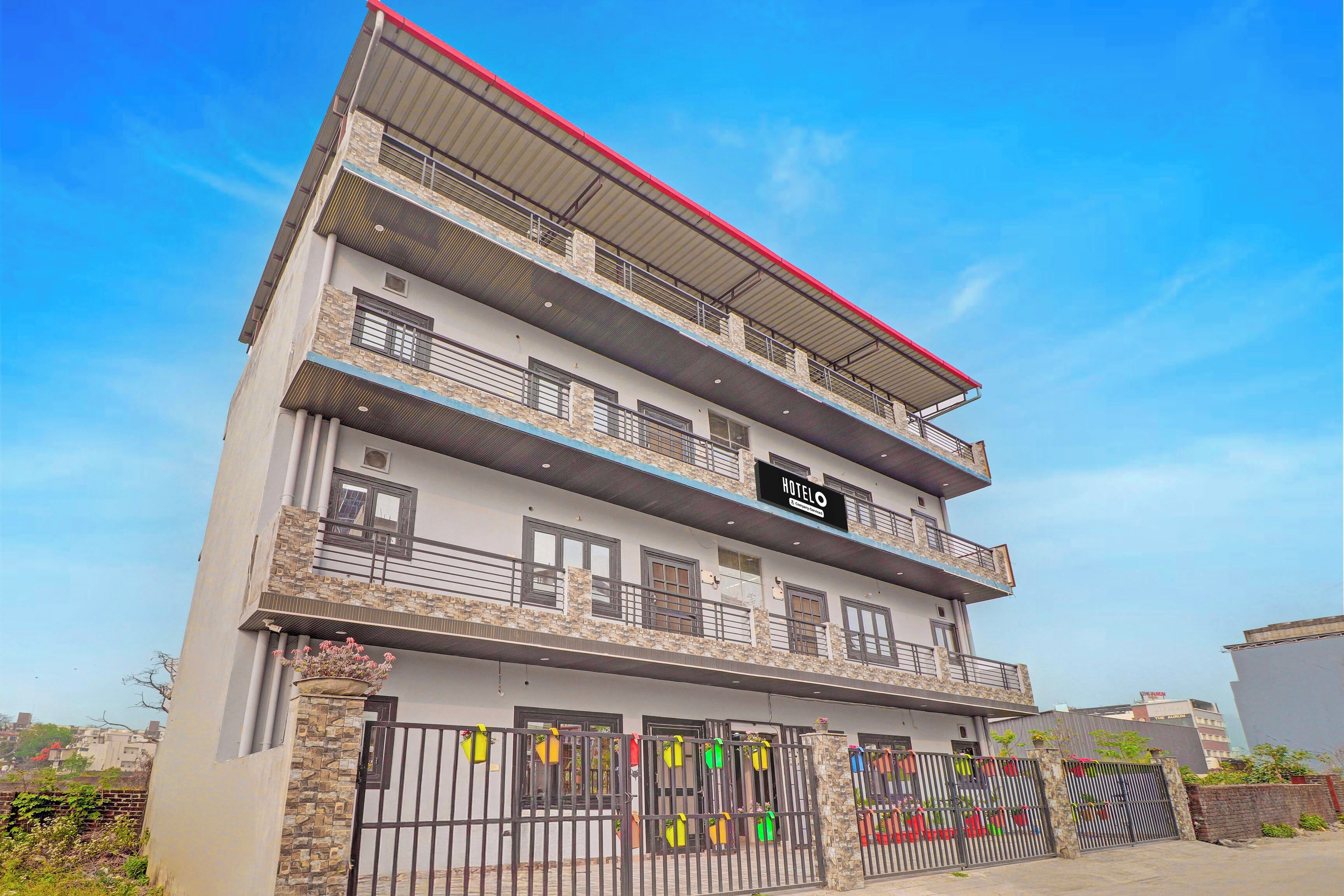 Un hotel de varios pisos con balcones, un letrero que indica que es un hotel y una entrada con portones.