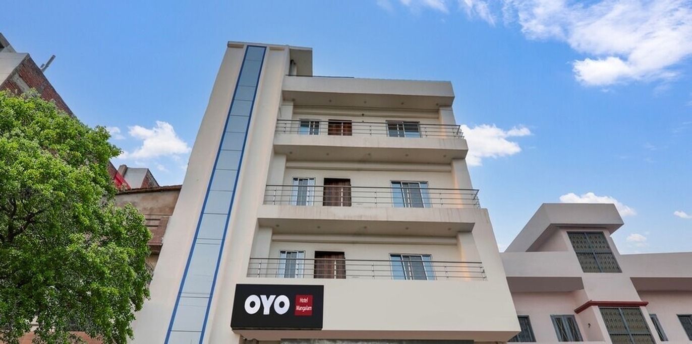 A multi-story hotel building with a sign for 'OYO Hotel Mangalam.'