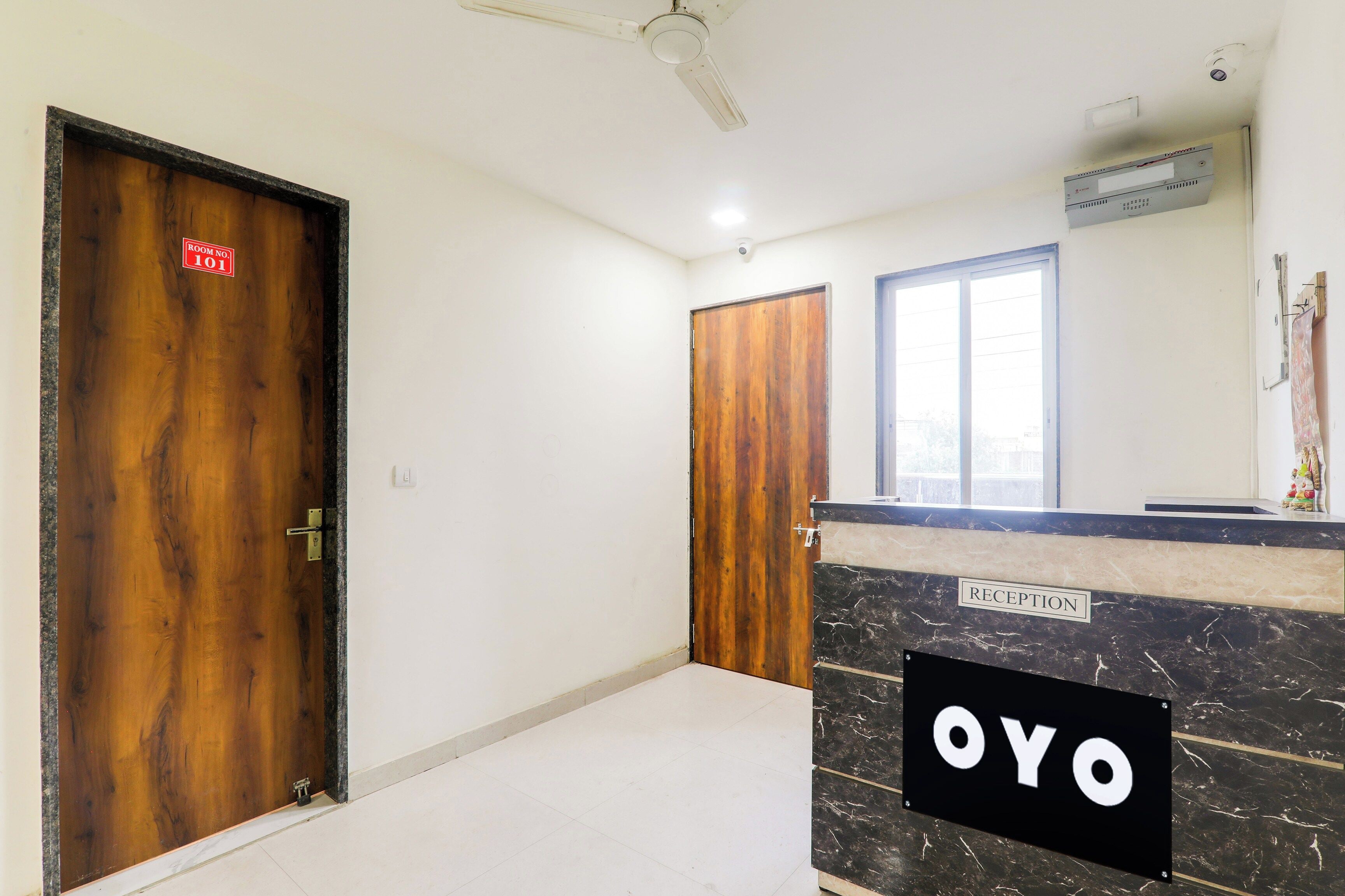 A hotel reception area with a marble counter, a reception sign, and two wooden doors.
