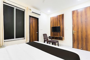 A hotel room with a large bed, a TV mounted on the wall, a wooden wardrobe, and a window with curtains. - Hotel O Manglam Hotel (Lucknow)