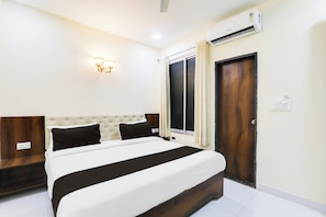 A hotel room with a bed, a wall-mounted air conditioner, a window with curtains, and a wall sconce. - Hotel O Manglam Hotel (Lucknow)