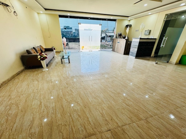 A spacious lobby with a marble floor, a sofa with cushions, a glass table, and a view through a glass door to the outside. - Hotel O Manglam Hotel (Lucknow)