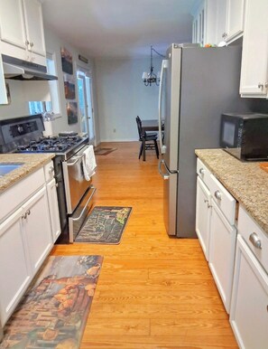 A kitchen with white cabinets, a stainless steel stove, a refrigerator, and a microwave. - Charming Lake Burton Cove Cottage 3BR/3BA Private 1 acre (Tiger)