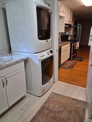 A compact kitchen with a built-in washer and dryer, a microwave, and a stove. - Charming Lake Burton Cove Cottage 3BR/3BA Private 1 acre (Tiger)