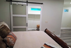 A bedroom with a bed, a sliding door, and a small stool. - Charming Lake Burton Cove Cottage 3BR/3BA Private 1 acre (Tiger)