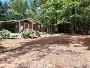 A rustic cabin with a porch, surrounded by a gravel driveway and a white picket fence. - Charming Lake Burton Cove Cottage 3BR/3BA Private 1 acre (Tiger)