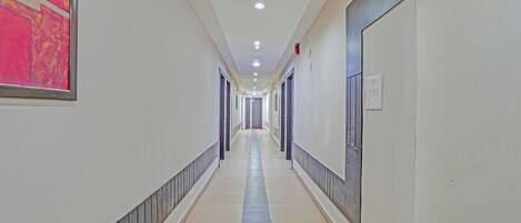 A long, narrow hallway with doors on both sides, recessed lighting, and a tiled floor.