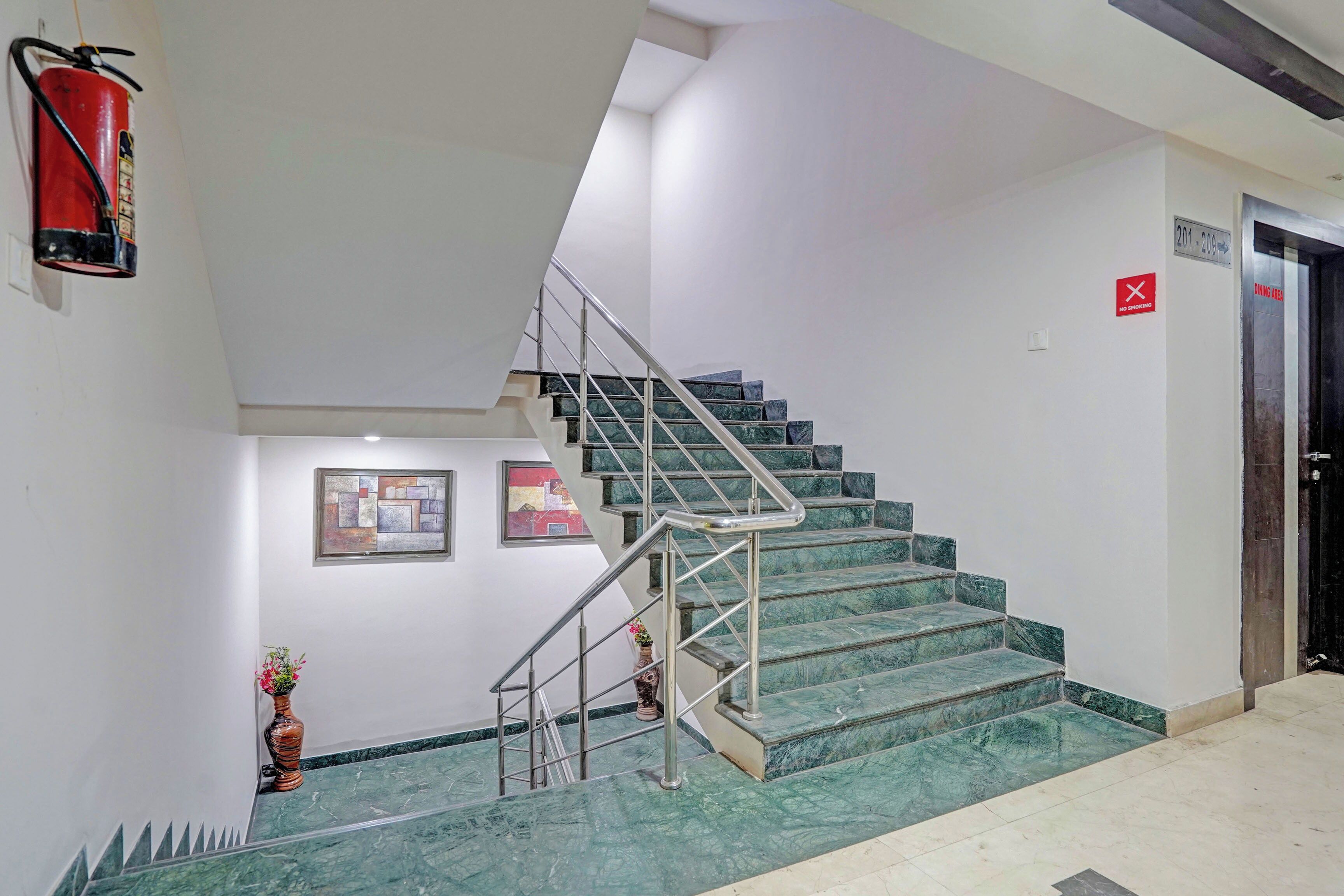 Una escalera con barandillas de metal y peldaños de mármol que lleva a un comedor señalado con un letrero rojo.