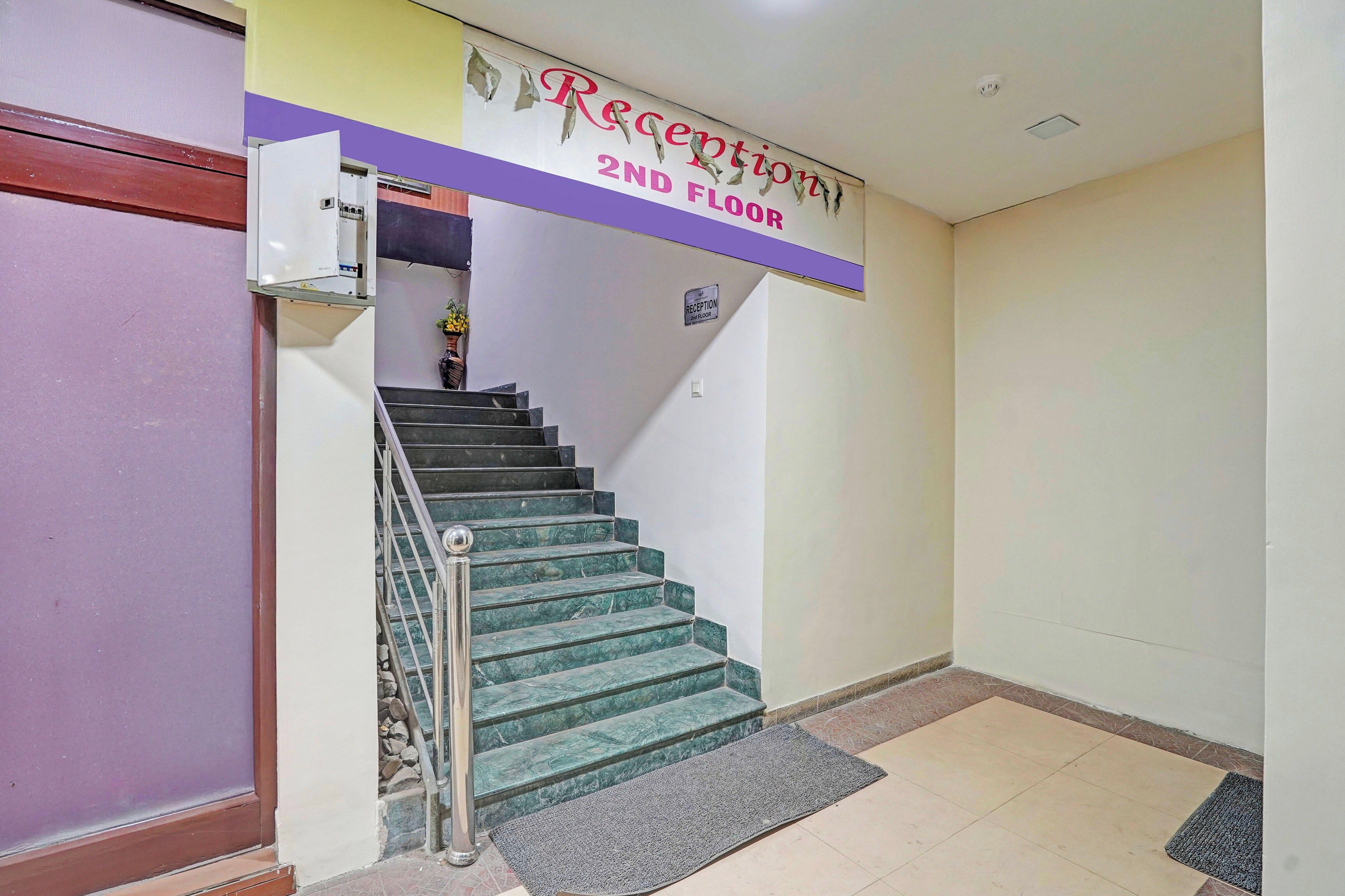A reception area with a staircase leading to the 2nd floor, a reception desk, and a wall-mounted sign indicating the floor.
