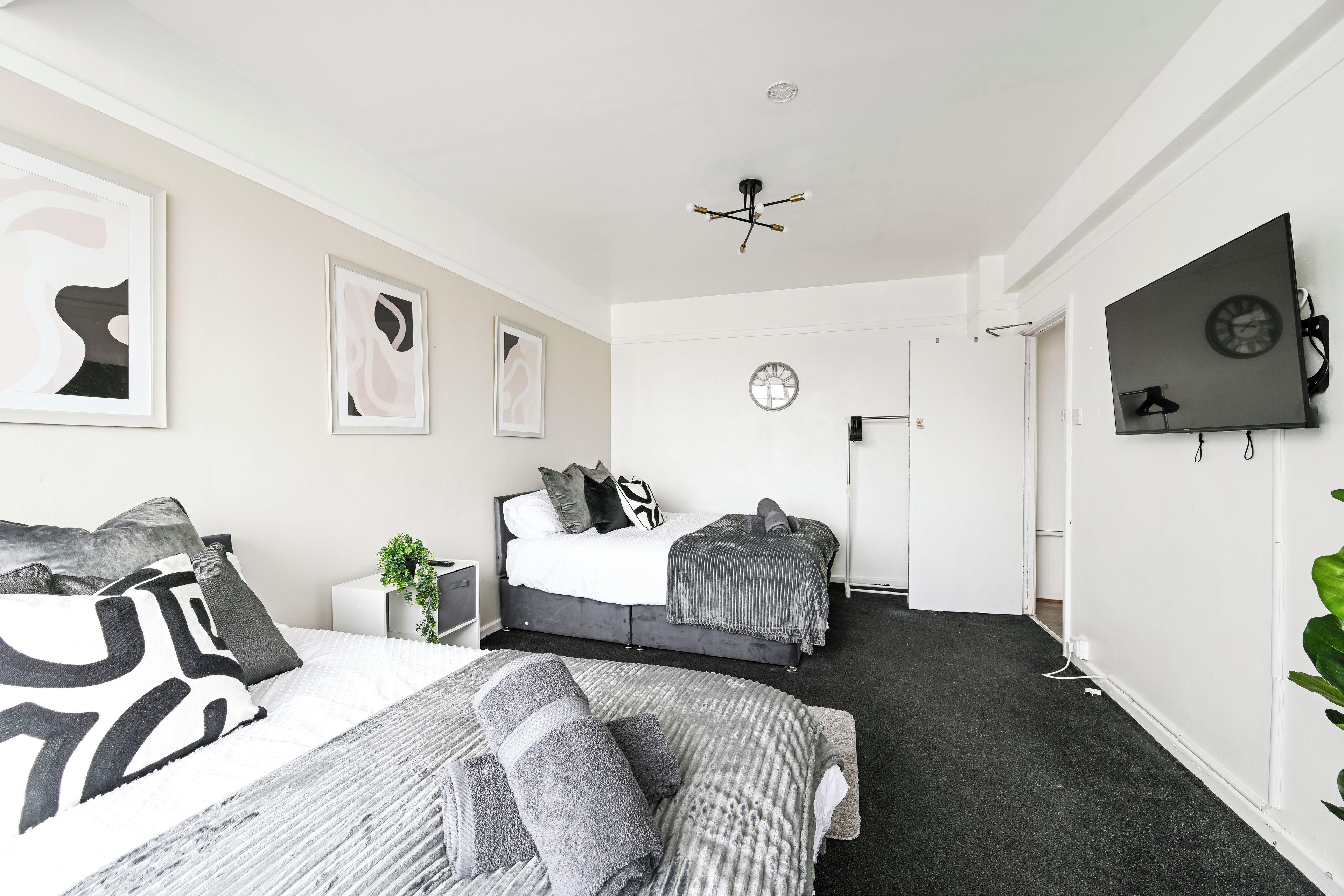 A modern bedroom with two beds, a large mirror, and abstract wall art.